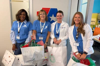 Group of 4 colleagues holding senior citizen gift bags.