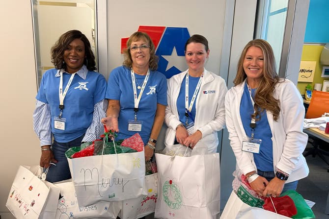 Group of 4 colleagues holding senior citizen gift bags.