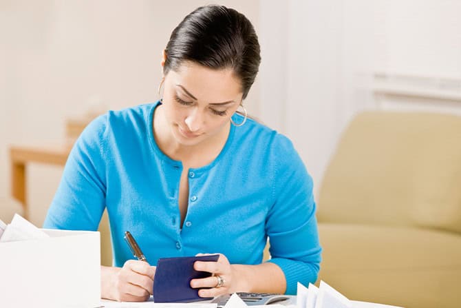 Women writing a check from her checkbook.