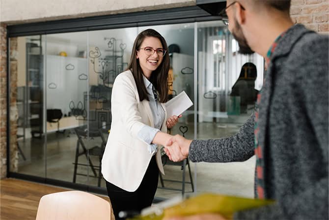 Professional women greeting a customer coming into office.