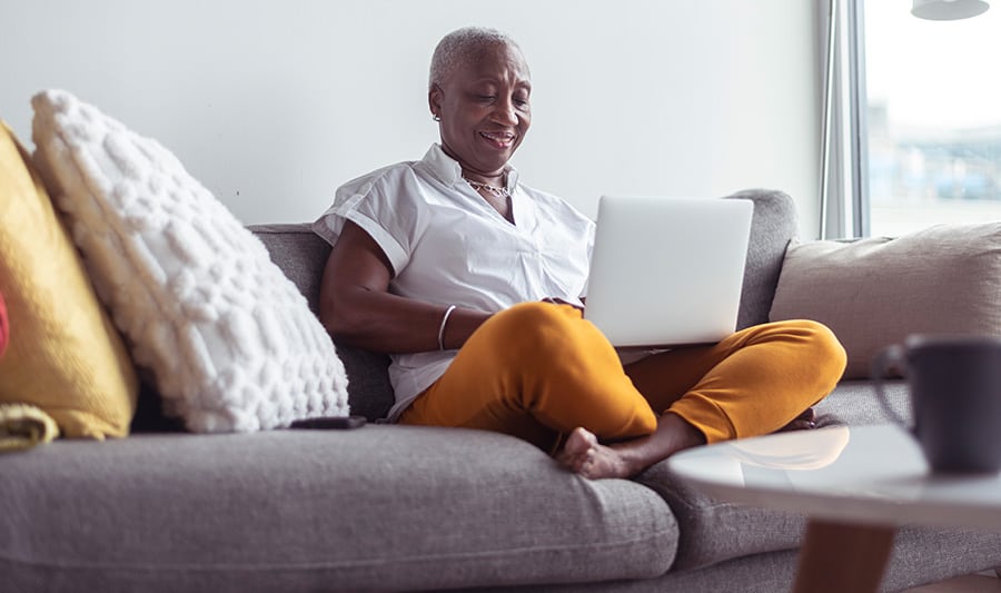 Senior person sitting on their couch with a laptop