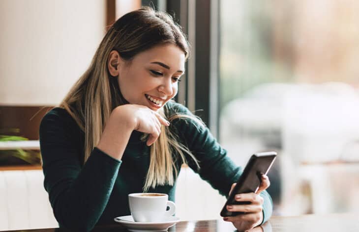 Women in coffee shop texting on her smart phone